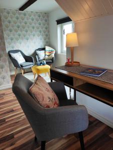 Gothem Viby Bed&Breakfast في Slite: غرفة معيشة مع مكتب وكرسي مع وسادة