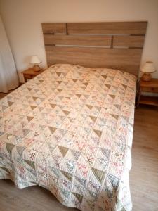 a bed with a quilt on it in a bedroom at Gite de charme Les Buissonnets in Plesder