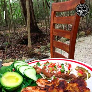un piatto di alimenti con carne e verdure su un tavolo di Aldea Maya-Ha Cabañas con cenotes a Puerto Morelos