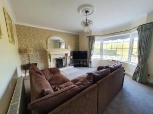a living room with a brown couch and a fireplace at Cosy Family home in Burnfoot