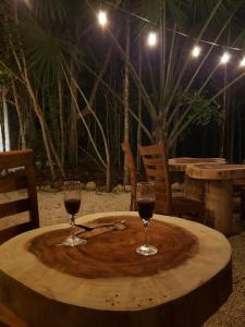 two glasses of wine sitting on a wooden table at Aldea Maya-Ha Cabañas con cenotes in Puerto Morelos