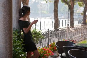 una mujer con un vestido negro sosteniendo un celular en Hotel Lenno en Lenno
