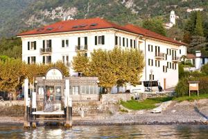 a large building on the water next to a house at Hotel Lenno in Lenno