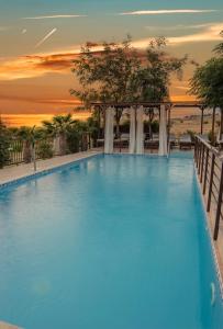 a large swimming pool with a sunset in the background at Victory Apartments & Hotel (Block C) in Samothráki