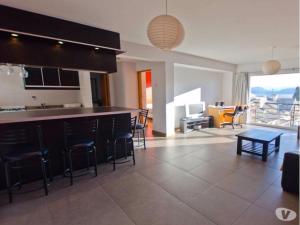 eine Küche mit einer Bar mit Stühlen und ein Wohnzimmer in der Unterkunft MODERNO DEPARTAMENTO CON VISTA AL LAGO in San Carlos de Bariloche