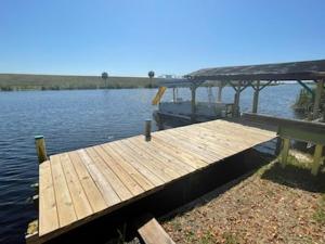 a wooden dock on a body of water at Rim Canal Cottage 'Yellow House' with Canal Views & Boat Dock cottage in Okeechobee