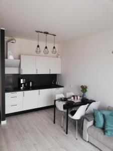 ein Wohnzimmer mit einem Tisch und einer Küche in der Unterkunft AL Mare Apartament in Danzig