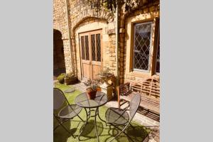 a patio with a table and chairs in front of a building at Over The Arches, Chipping Campden in Chipping Campden