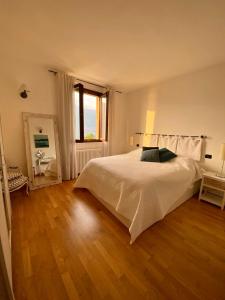 1 dormitorio con 1 cama blanca grande y suelo de madera en Appartment in Blevio; stunning view of the lake, en Blevio