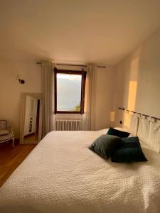 una camera da letto con un grande letto bianco e una finestra di Appartment in Blevio; stunning view of the lake a Blevio