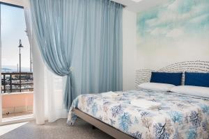una camera da letto con un letto con tende blu e una finestra di Acquazzurra Gaeta a Gaeta