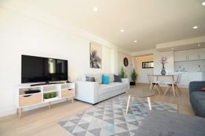 ein Wohnzimmer mit einem weißen Sofa und einem Flachbild-TV in der Unterkunft Les Volets Bleus in Nizza