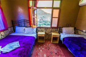 two beds in a room with a window at Les Jardins De Todgha gorges de todra tinghir in Aït Baha