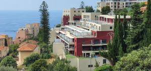 a red building on the side of a hill with houses at Monaco view, pool, garage, 100 m2 terrace in Beausoleil