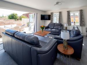 a living room with a blue leather couch and chairs at Lemonade Cottage in Whitby