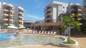 a swimming pool with a palm tree in front of a building at Privé Marina flat Apart in Caldas Novas
