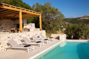 un grupo de tumbonas junto a la piscina en Villa Elanthy-New Luxury villa with private sea access, en Sivota