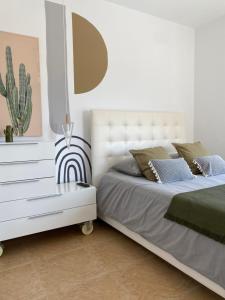 a white bedroom with two beds and a dresser at EBLI House in San Miguel de Salinas