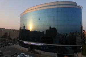 a large glass building with the reflection of the sunset at Grand Mayral Hotel in Al Khobar