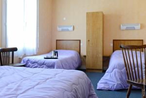 a room with two beds with purple sheets at Le Clos Normand in Troarn