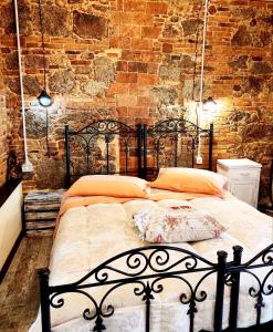 un letto nero in una stanza con un muro di mattoni di Il Vico a Serra San Bruno