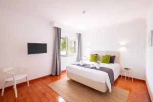 a white bedroom with a bed and a chair at Villa Benagil Boutique by Algarve Vacation in Carvoeiro +42 photos