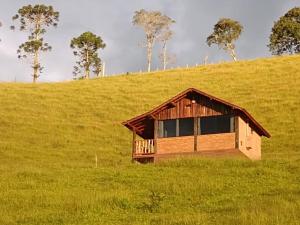 a house on top of a hill in a field at Pousada Rancho da Montanha in Visconde De Maua