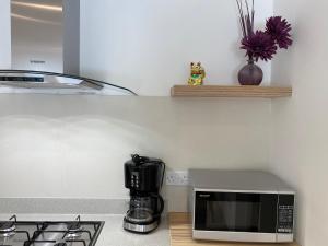 eine Küche mit einer Mikrowelle und einer Kaffeemaschine auf der Theke in der Unterkunft Amber Lodge Hickstead-B in Burgess Hill