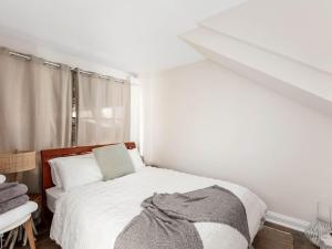 a white bedroom with a bed and a window at Blue View Gerringong in Gerringong