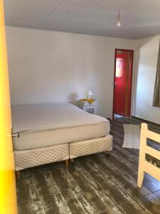 1 dormitorio con 1 cama grande y puerta roja en Casa da Praia - Rancho da Pedra en Itapoa