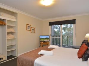 a bedroom with a large bed and a television at Villa 3br De Saran Villa located within Cypress Lakes Resort in Pokolbin
