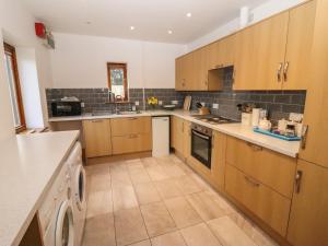 a kitchen with wooden cabinets and a dishwasher at Hill Farm Cottage in Bacton