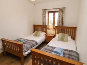 two twin beds in a room with a window at Hill Farm Cottage in Bacton