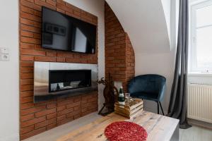 a living room with a brick fireplace with a television on a wall at Sofia Apartment & Zimmer in Sillweg