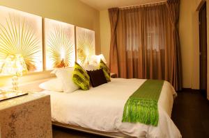 a bedroom with a large bed with green and white pillows at Plaza Gallery Hotel Boutique in San Cristóbal de Las Casas
