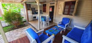 un porche con 2 sillas azules y una mesa en Les Bungalows Couleurs Soleil, en Le Vauclin