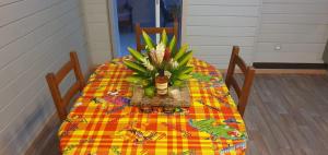 Una mesa con un jarrón de flores encima. en Les Bungalows Couleurs Soleil, en Le Vauclin