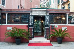 ein rotes Gebäude mit zwei Pflanzen davor in der Unterkunft Hotel La Fenice et Des Artistes in Venedig