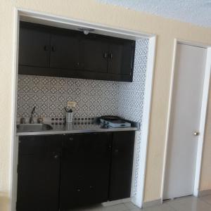 a kitchen with black cabinets and a sink at Suite en torres gemelas vista al mar in Acapulco