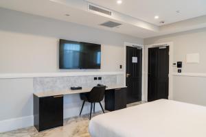 um quarto de hotel com uma cama e uma secretária com uma televisão em Holiday Inn & Suites - Parramatta Marsden Street, an IHG Hotel em Sidney
