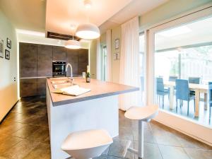 uma cozinha com um lavatório e um balcão com bancos em Lush holiday home on the edge of the Hautes Fagnes em Waimes