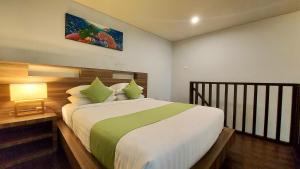 a bedroom with a large bed with green and white sheets at The New Moon Seminyak in Seminyak