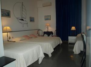 Habitación de hotel con 2 camas y escritorio en Hotel La Conchiglia, en La Maddalena