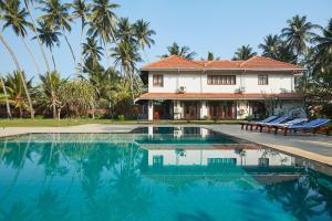 a house with a swimming pool in front of a house at The Beach Villas by Ceylon Bungalows in Wadduwa