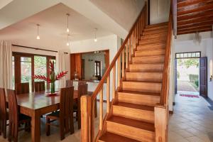 a dining room and kitchen with a wooden staircase at The Beach Villas by Ceylon Bungalows in Wadduwa