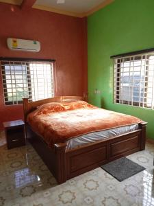 een slaapkamer met een bed met groene muren en ramen bij Justa Hotel Annex in Accra