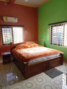 a bedroom with a bed with green walls and windows at Justa Hotel Annex in Accra