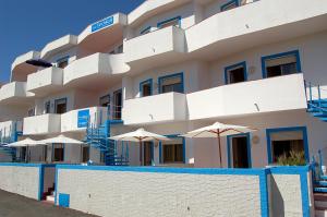 
a row of white and blue houses with white umbrellas at Case Vacanze Farchikalà in Lampedusa
