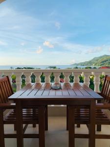 - Balcón con mesa de madera y 2 sillas en Oceanic View Apartments, en Beau Vallon