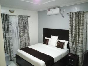 - une chambre avec un grand lit blanc et des rideaux dans l'établissement Room in Lodge - Blooms Spot Hotel and Suites, à Port Harcourt